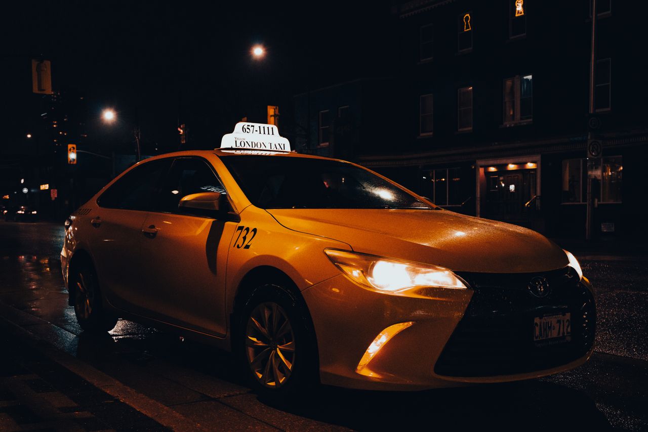 Services A yellow taxi waiting at night in London, Ontario, Canada. Urban transportation captured with street lights.